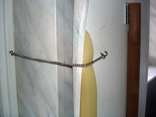 Metal chain holds ironing board in place against the wall